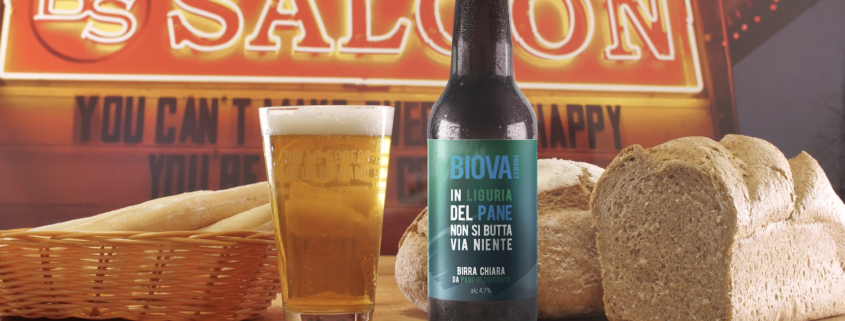 Bottiglia di birra Biova Liguria su banco con pane e insegna Saloon sullo sfondo